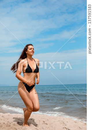 Fit woman running on sandy beach in bikini, enjoying summer sun and using sunscreen lotion for UV protection and skincare routine Fit woman running on sandy beach in bikini, enjoying summer sun and using sunscreen lotion for UV protection and skincare routine 137591583