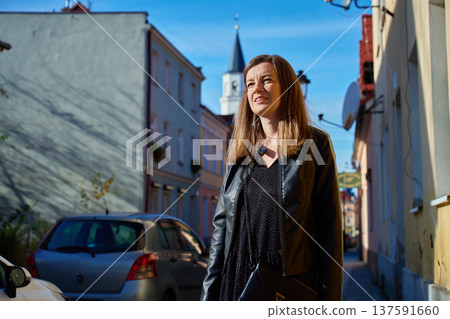 Woman standing on sunny city street with tower behind Woman standing on sunny city street with tower behind 137591660