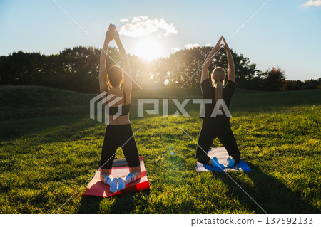 Yoga practice under the serene sunset in a tranquil park setting Yoga practice under the serene sunset in a tranquil park setting 137592133