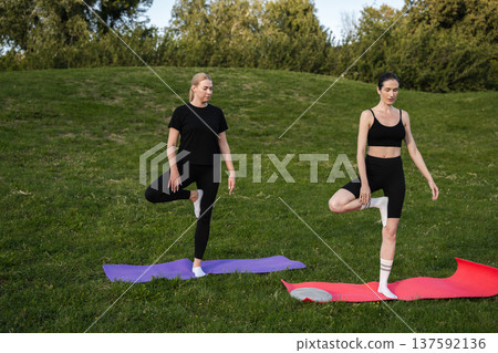 Women practicing yoga together on colorful mats in a sunny park Women practicing yoga together on colorful mats in a sunny park 137592136