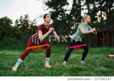 Women exercising with resistance bands in a sunny park during morning hours 137592137