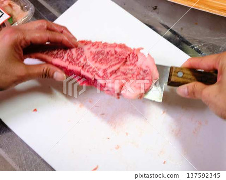 A female chef cutting domestically produced Japanese Black beef thigh meat 137592345