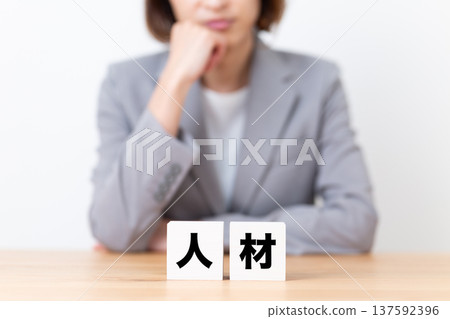 A middle-aged woman in a suit worried about a human resources block A middle-aged woman in a suit worried about a human resources block 137592396