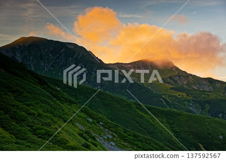 Mount Mitsumatarenge seen from Sugoroku hut in the Northern Alps, with clouds drifting by at sunset Mount Mitsumatarenge seen from Sugoroku hut in the Northern Alps, with clouds drifting by at sunset 137592567
