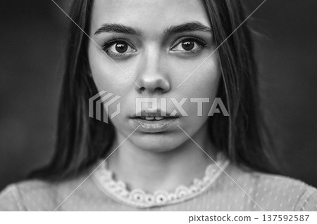 Black and white close up portrait of a beautiful young woman with expressive eyes looking at camera 137592587