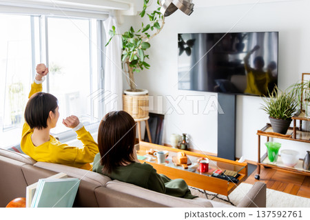 Two women watching TV together Two women watching TV together 137592761