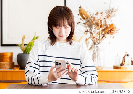 Woman looking at smartphone in the room Woman looking at smartphone in the room 137592800