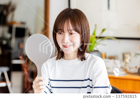 Woman looking in a hand mirror Woman looking in a hand mirror 137592815