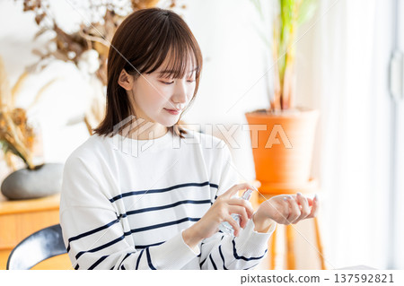 Woman spraying perfume on her wrist Woman spraying perfume on her wrist 137592821