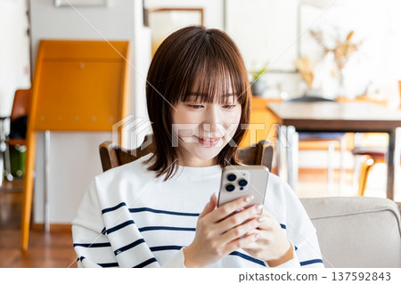 A woman who operates a smartphone in the room 137592843