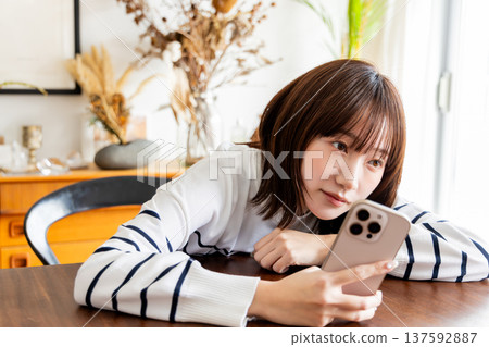 A woman looking at her smartphone in the living room A woman looking at her smartphone in the living room 137592887