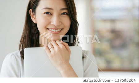Smiling woman holding a laptop Generative AI 137593204