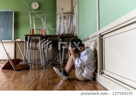 Boy crouching in classroom Boy crouching in classroom 137593255