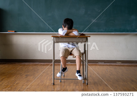 一名小學生臉朝下趴在教室的桌子上睡覺。 一名小學生臉朝下趴在教室的桌子上睡覺。 137593271