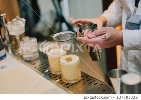 Bartender prepares cocktails at bar during service 137593329