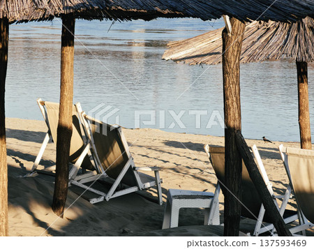 Deck chairs under straw umbrellas Deck chairs under straw umbrellas 137593469