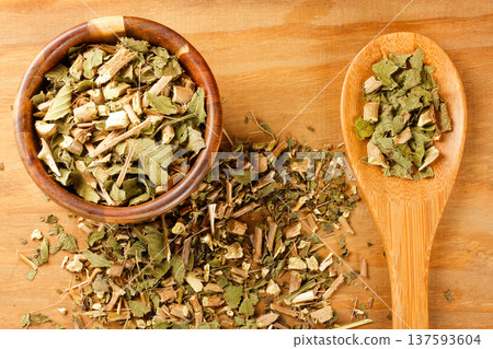 Dried lemon balm leaves, Melissa officinalis, in a handcrafted bowl with a wooden spoon on a rustic wooden background 137593604