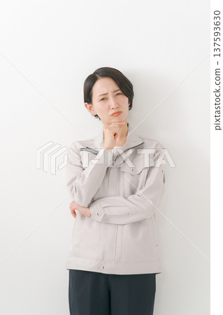 A woman in work clothes who is worried A woman in work clothes who is worried 137593630