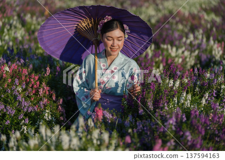 woman in yukata (kimono dress) holding umbrella with angelonia flower blooming in garden woman in yukata (kimono dress) holding umbrella with angelonia flower blooming in garden 137594163