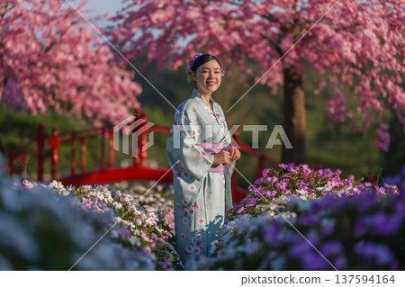 woman in yukata (kimono dress) with sakura flower or cherry blossom blooming in garden 137594164