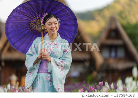 woman in yukata (kimono dress) holding umbrella with angelonia flower blooming in garden 137594168