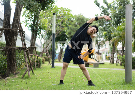 A man performs a side bend stretch outdoors, extending his torso to stretch oblique and side muscles, improving flexibility and body mobility. A man performs a side bend stretch outdoors, extending his torso to stretch oblique and side muscles, improving flexibility and body mobility. 137594997