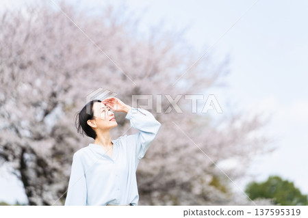 Young woman posing in front of a cherry blossom tree Lifestyle image Young woman posing in front of a cherry blossom tree Lifestyle image 137595319