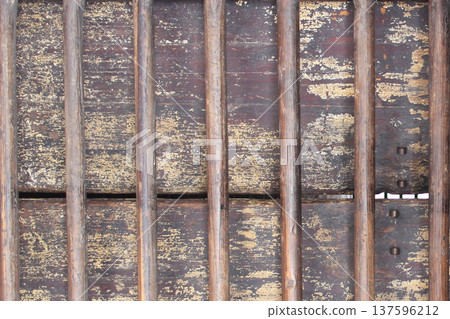 Old weathered wooden surface with vertical metal bars forming a rustic antique texture, ideal as vintage wallpaper, historical background, or ancient architectural design element. Old weathered wooden surface with vertical metal bars forming a rustic antique texture, ideal as vintage wallpaper, historical background, or ancient architectural design element. 137596212