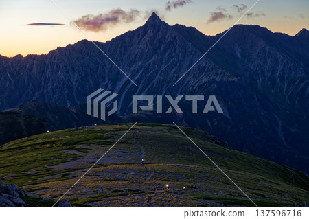 從雙六山眺望北阿爾卑斯山脈、槍岳以及黎明時分登山者的燈光。 從雙六山眺望北阿爾卑斯山脈、槍岳以及黎明時分登山者的燈光。 137596716