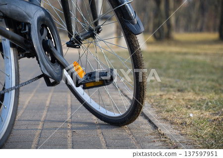 Bicycle Wheel And Pedal On A Park Path With Muddy Tire And Reflector 137597951