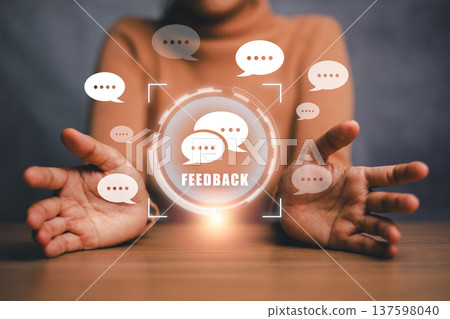 Hands presenting a digital feedback icon surrounded by speech bubbles, symbolizing communication and interaction. Hands presenting a digital feedback icon surrounded by speech bubbles, symbolizing communication and interaction. 137598040