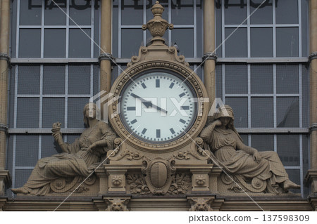 Historic clock tower facade at railway station featuring classical sculptures architectural design Historic clock tower facade at railway station featuring classical sculptures architectural design 137598309