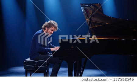 musician passionately plays grand piano under dramatic stage lighting, creating emotional atmosphere musician passionately plays grand piano under dramatic stage lighting, creating emotional atmosphere 137598549