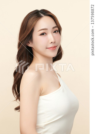 A beautiful young Asian woman with clean, fresh skin against a beige background. Skincare, facial treatment, cosmetology, beauty, and spa. An elegant portrait of an Asian woman. 137598872