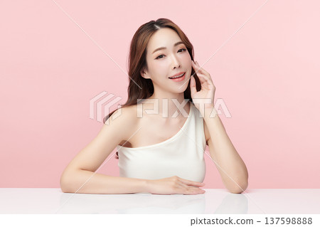 A beautiful young Asian woman with clean, fresh skin against a pink background. Skincare, facial treatment, cosmetology, beauty, and spa. An elegant portrait of an Asian woman. 137598888
