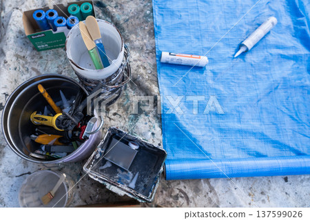 外牆塗裝場地準備:密封膠和施工工具擺放在藍色防水布上。 外牆塗裝場地準備:密封膠和施工工具擺放在藍色防水布上。 137599026