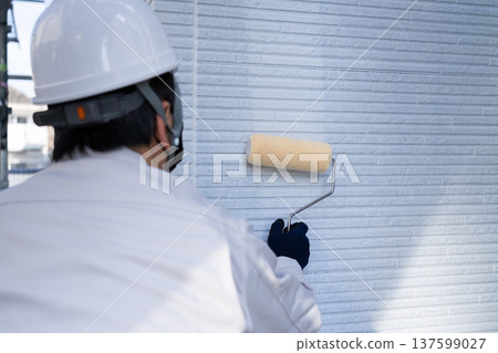 Male worker applying the base coat for exterior wall painting 137599027