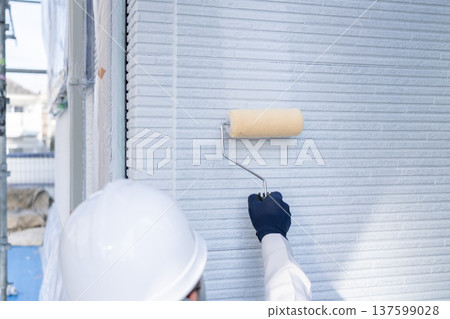 Male worker applying the base coat for exterior wall painting 137599028