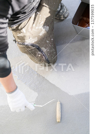 Balcony waterproofing maintenance: Worker applying waterproofing material with a long-handled roller Balcony waterproofing maintenance: Worker applying waterproofing material with a long-handled roller 137599035