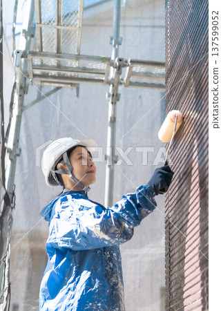 The forefront of home renovation: A female painter painting a wall with a bright smile The forefront of home renovation: A female painter painting a wall with a bright smile 137599052