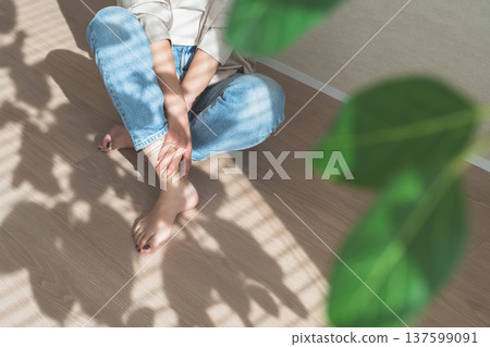 夕陽西下，一位身穿牛仔服的女子坐在木地板上。 137599091