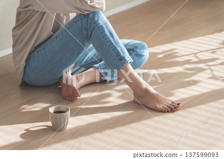 夕陽西下，一位身穿牛仔服的女子坐在木地板上。 137599093