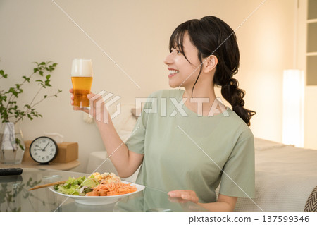 Young Asian woman having a drink in the bedroom at home (beer, home drinking, drinking habits) 137599346