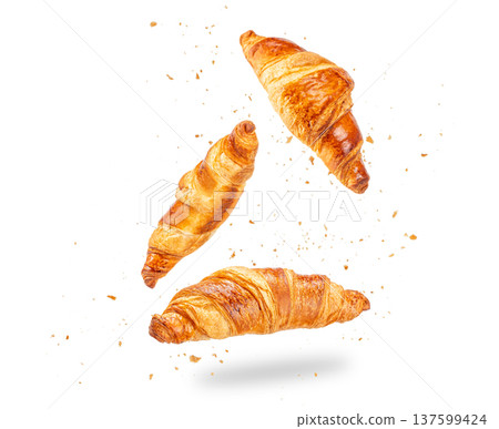 Three croissants flying with crumbs isolated on white background 137599424