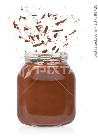 Chocolate shards falling into jar of chocolate spread isolated on white Chocolate shards falling into jar of chocolate spread isolated on white 137599426