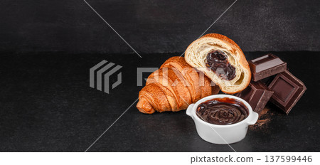 Chocolate croissant with chocolate spread bowl and dark chocolate pieces on dark background with copy space Chocolate croissant with chocolate spread bowl and dark chocolate pieces on dark background with copy space 137599446