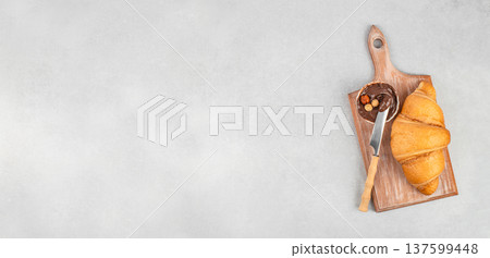 Croissant with chocolate spread and knife on wooden board with copy space 137599448
