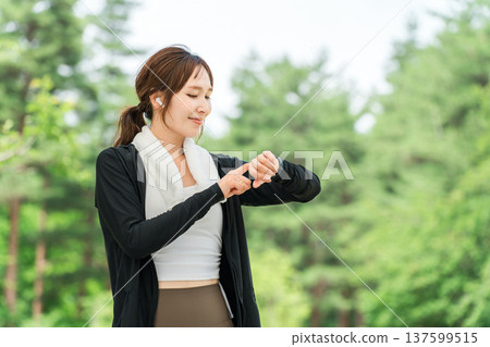 A woman operating a smartwatch while exercising (healthcare, music, workout) 137599515
