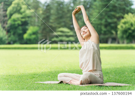 Young Asian woman doing park yoga, yoga, pilates, stretching in forest/park 137600194