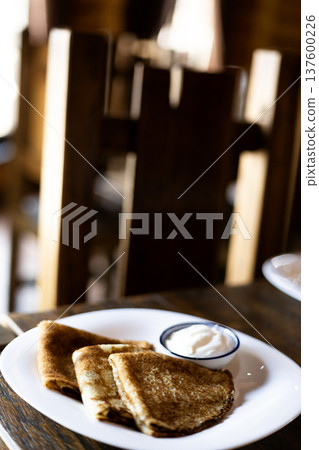 Stack of homemade crepes with sour cream on a plate on dark background traditional comfort food concept 137600226